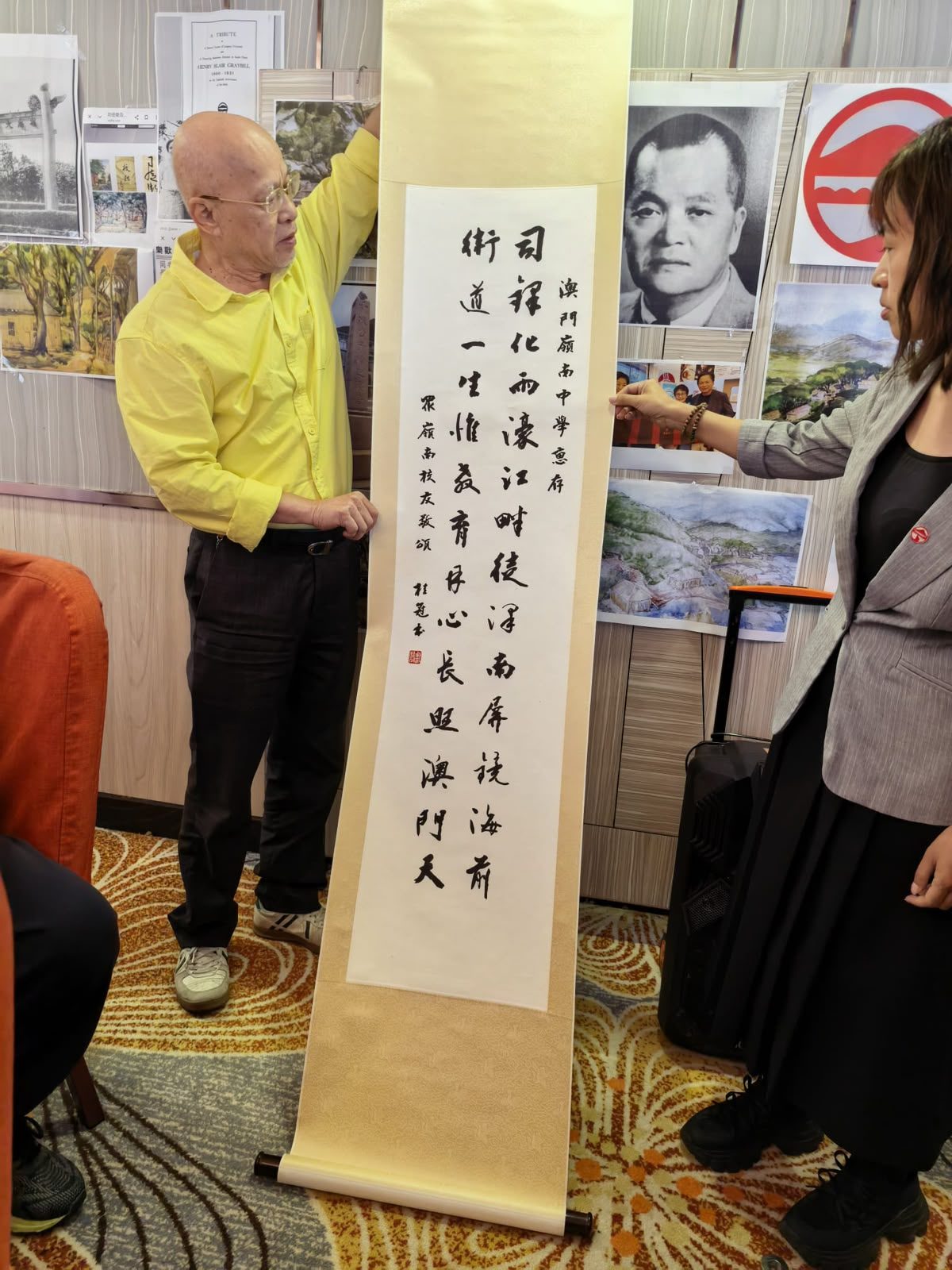 校友致送字畫，上款書「澳門嶺南中學惠存」，下款「眾嶺南校友敬頌」。左為戴桂冠學長，右為澳門嶺南中學代表黃苑芳副校長。
