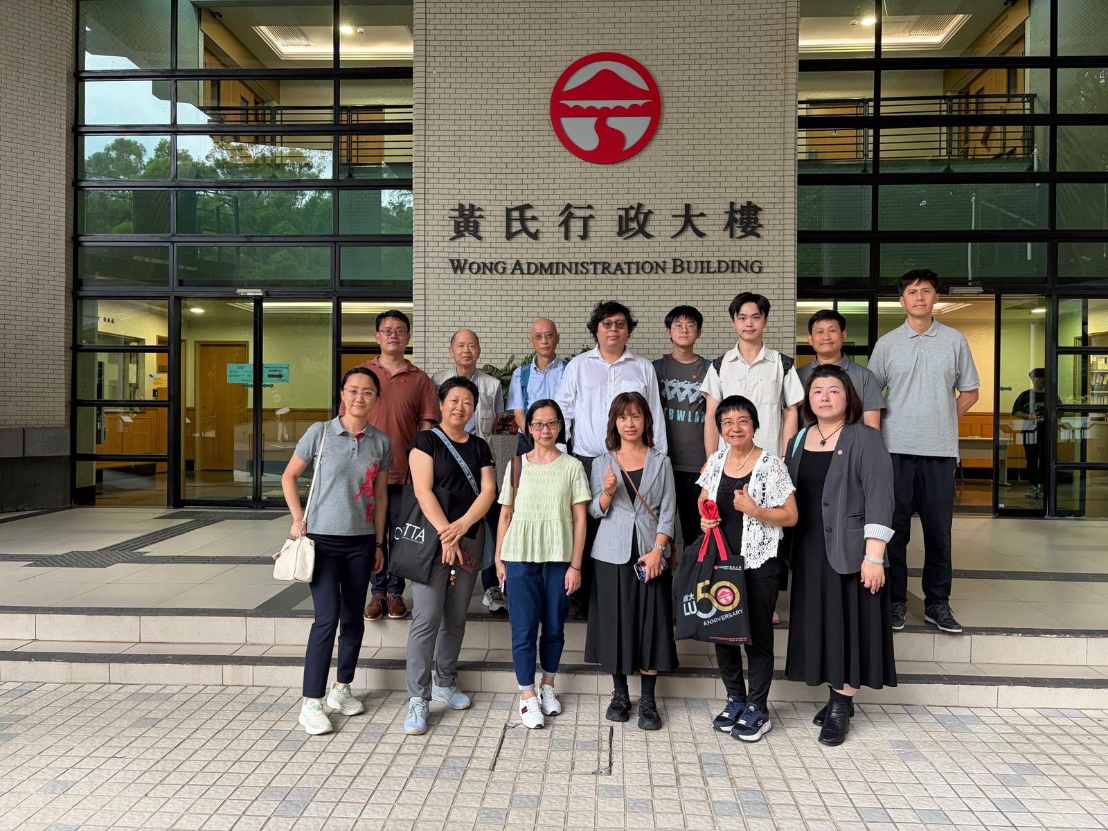黃氏行政大樓前合照，門楣上懸嶺南校徽。