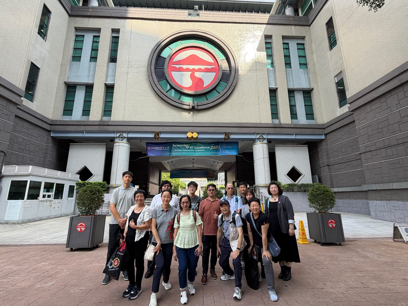 校園大樓正門前留影，巨型校徽高懸其上。